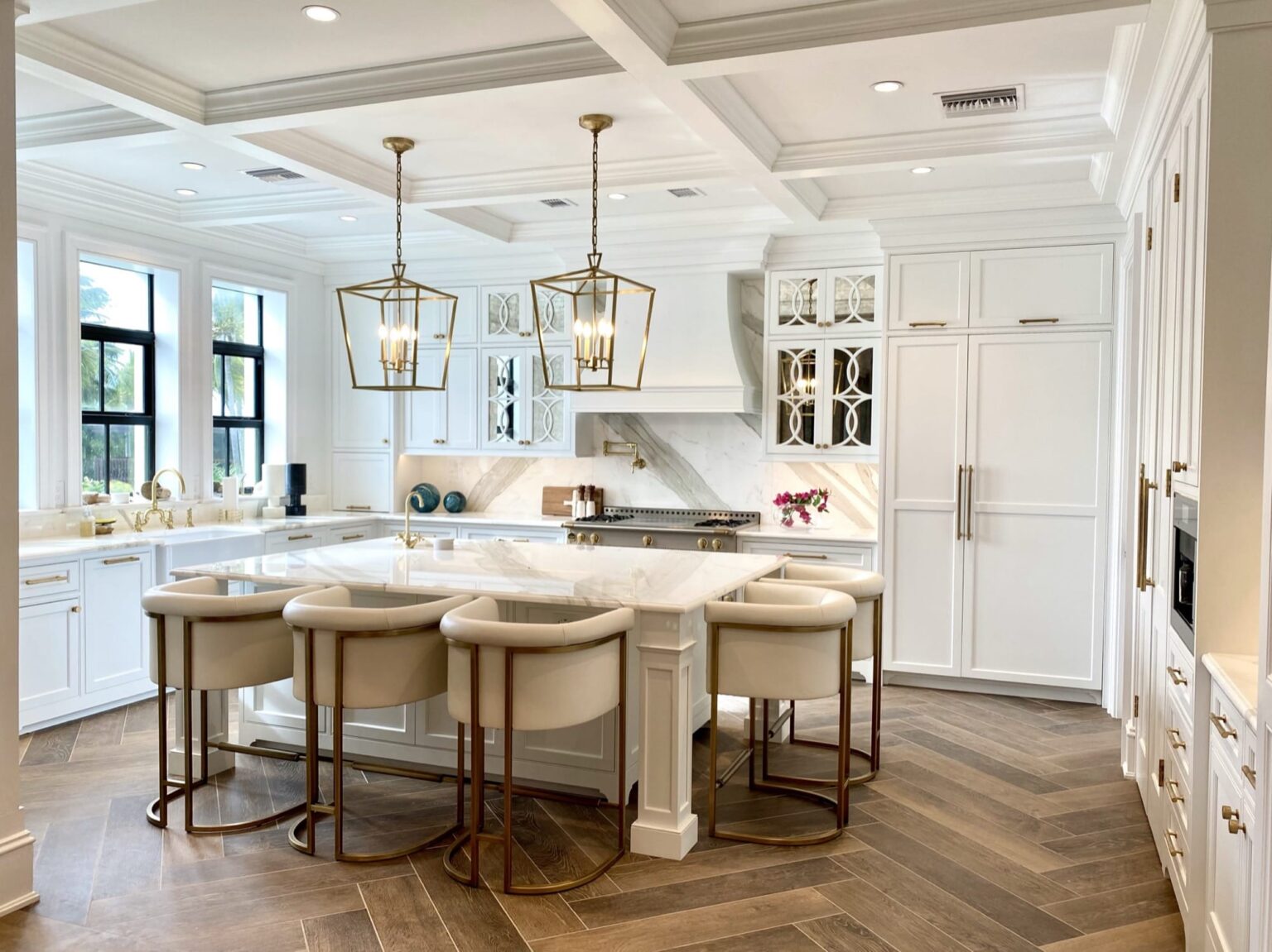 Bright white kitchen with a coffered ceiling, island and upholstered counter stools